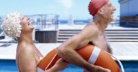 Side view of senior couple poolSide laughing and holding a lifebuoy