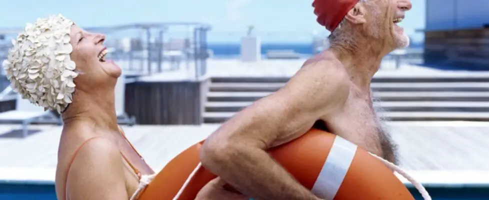 Side view of senior couple poolSide laughing and holding a lifebuoy